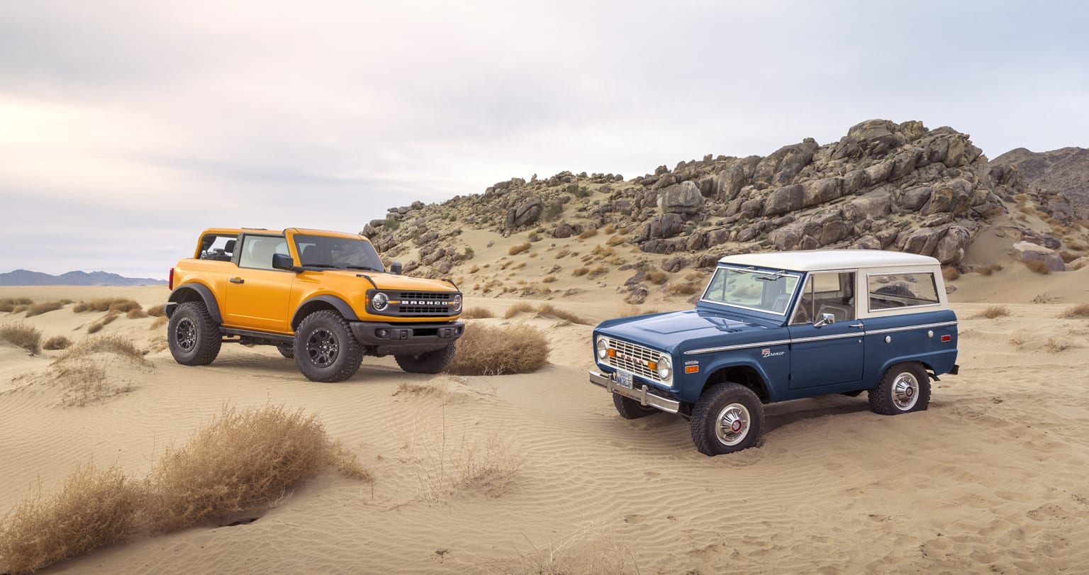 a couple of trucks that are sitting in the sand in the sand dunes of a desert with a mountain in the background