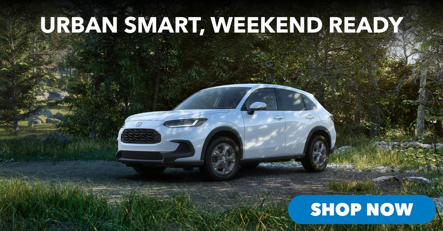 A white SUV parked on a dirt path in a forest.