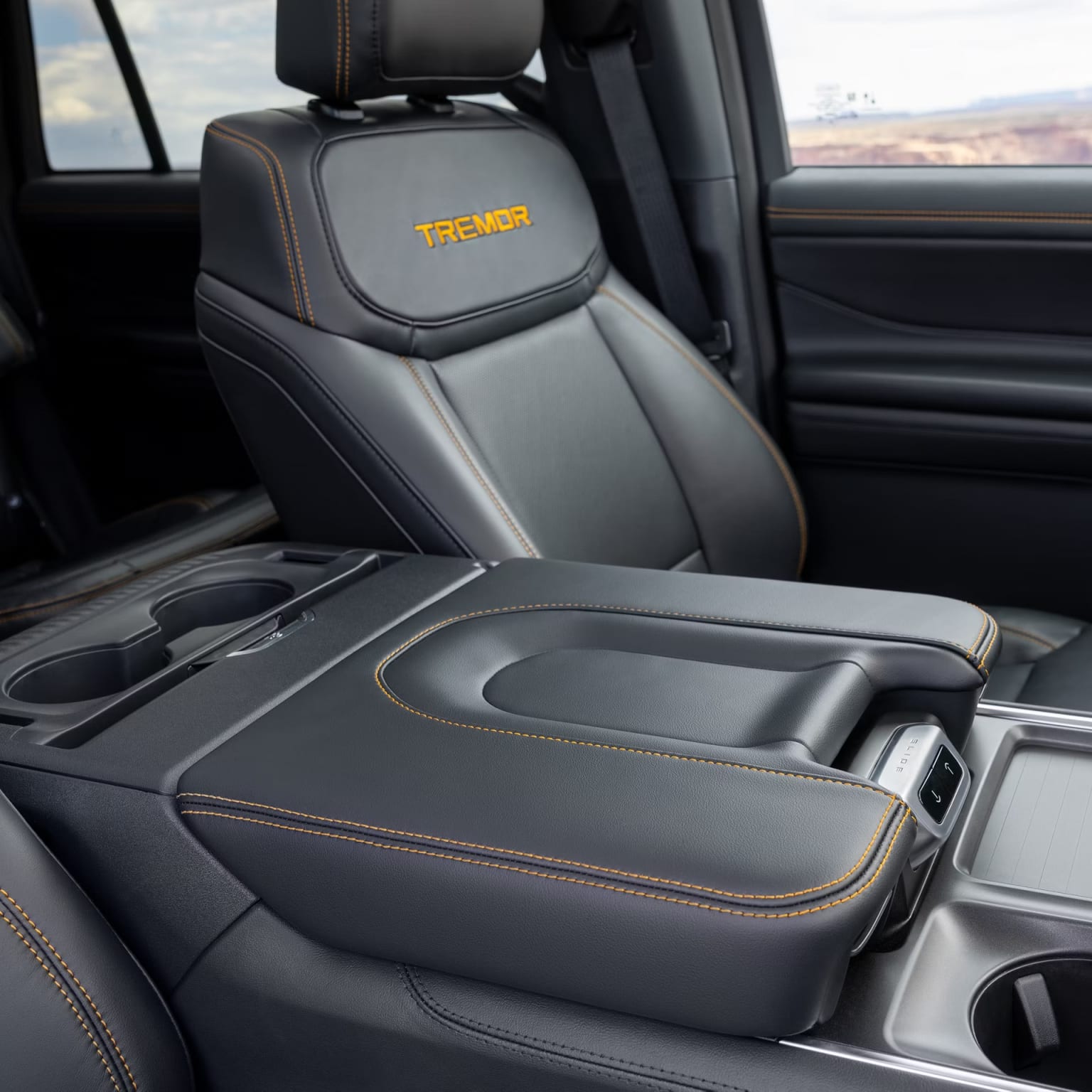 The image shows the interior of a vehicle, with a center console and leather-upholstered seats. The center console features a prominent logo, indicating this is likely the interior of a pickup truck.