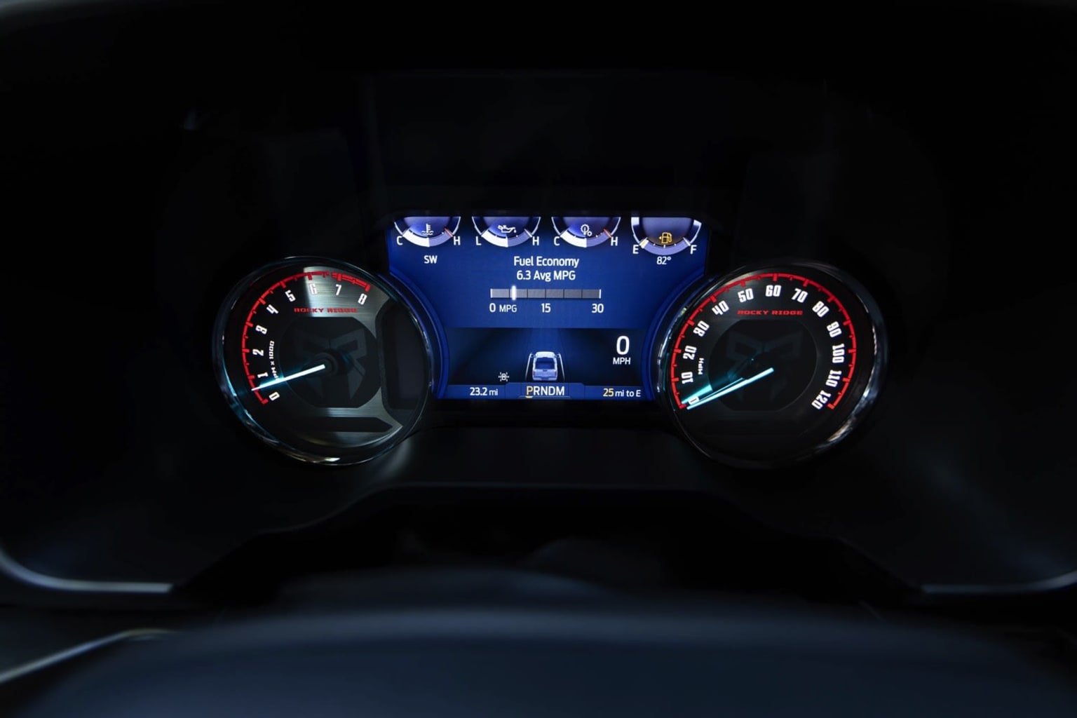 The image displays the dashboard of a vehicle with illuminated gauges and displays in a dark interior. Key features include the speedometer, tachometer, and other indicators showing the vehicle's status.