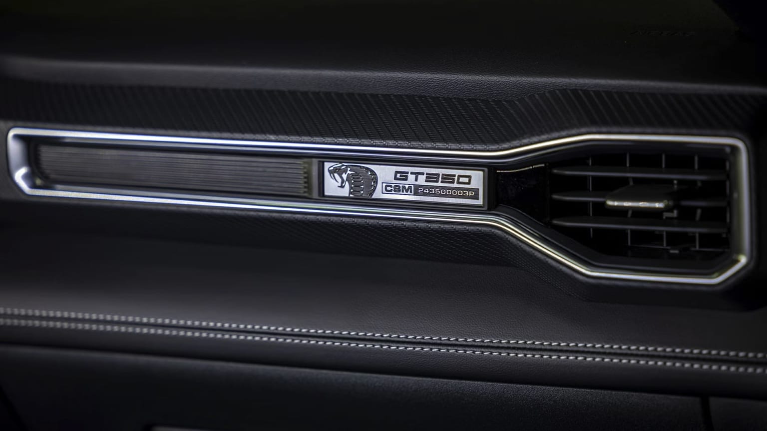 A close-up view of the front grille of a dark-colored vehicle, featuring the "GT350" badge and a sleek, aerodynamic design.