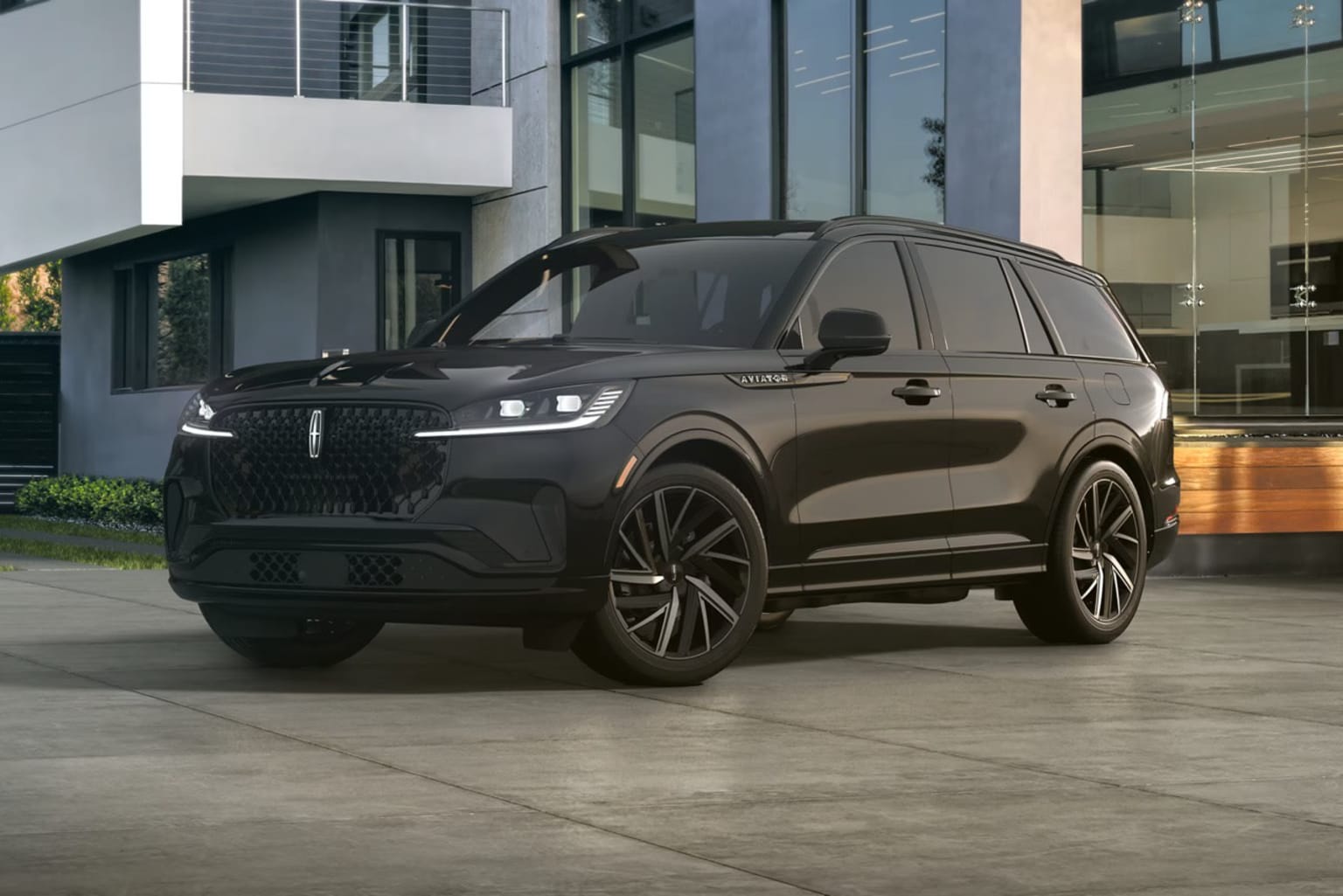 A large black SUV parked in front of a modern glass-fronted building.