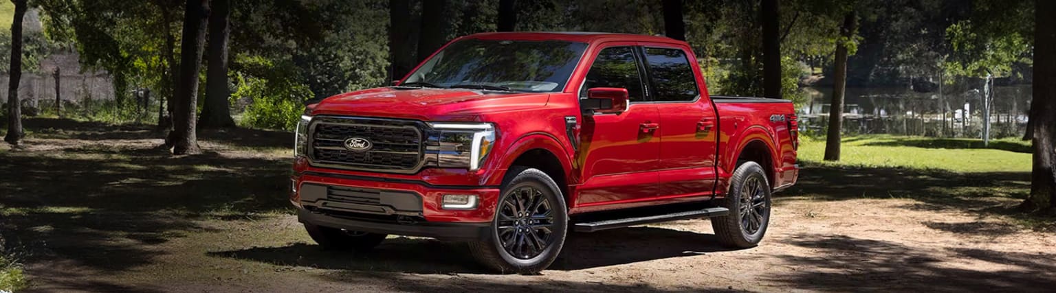 A bright red pickup truck in a lush, forested environment.