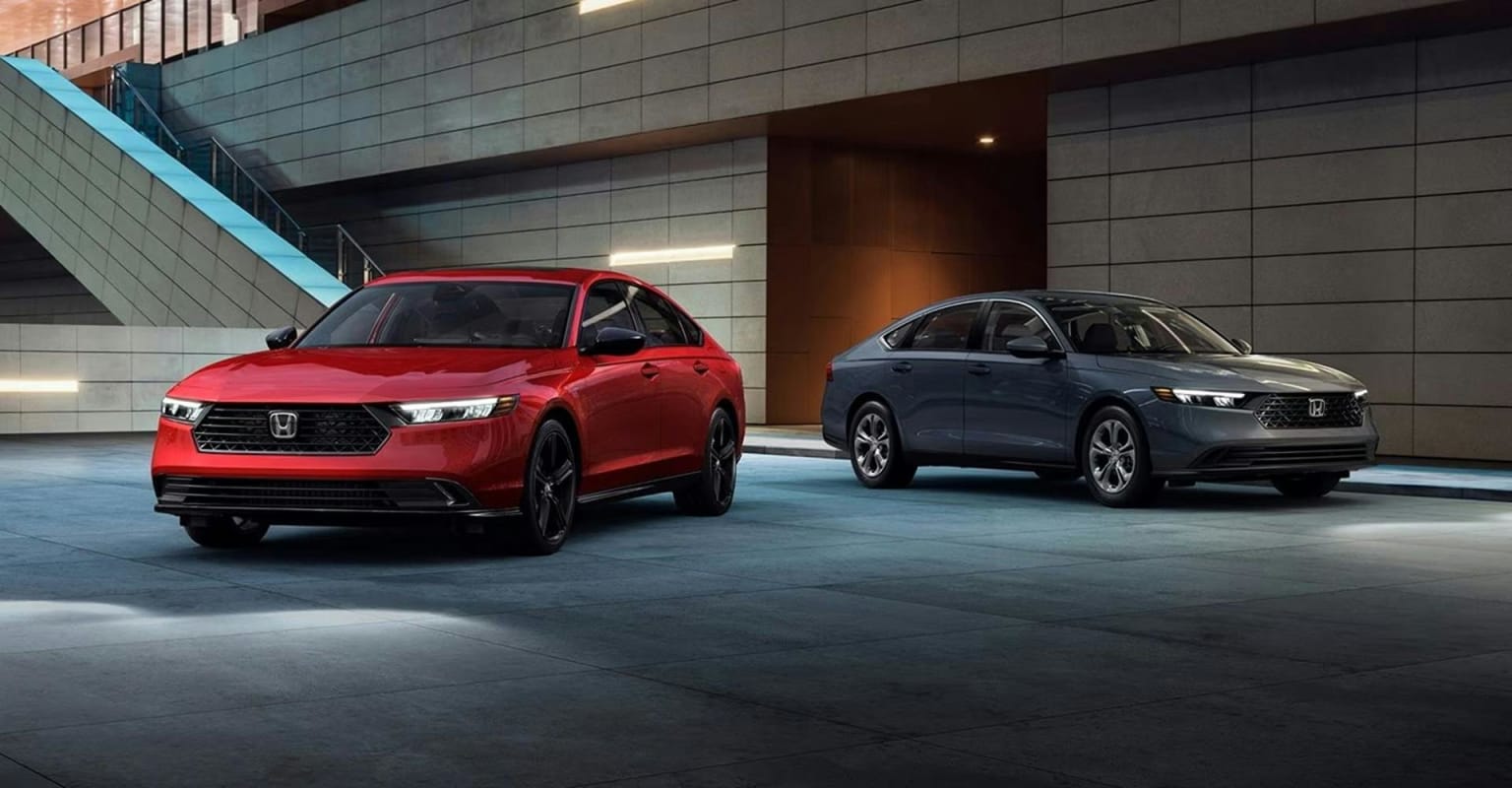 Two sedans in different colors parked in a modern, urban setting with concrete architecture.