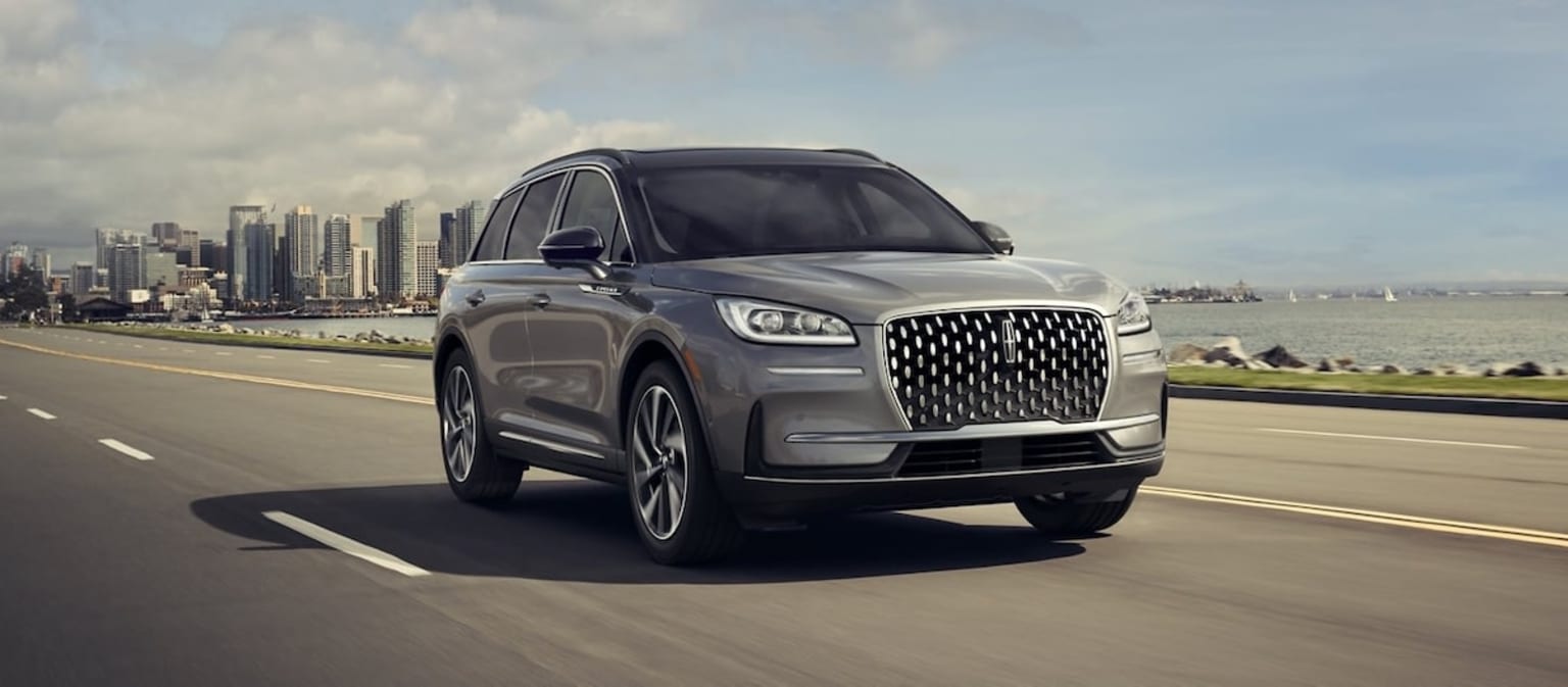 2025 Lincoln Corsair- Gray exterior driving down the highway away from city skyscrapers