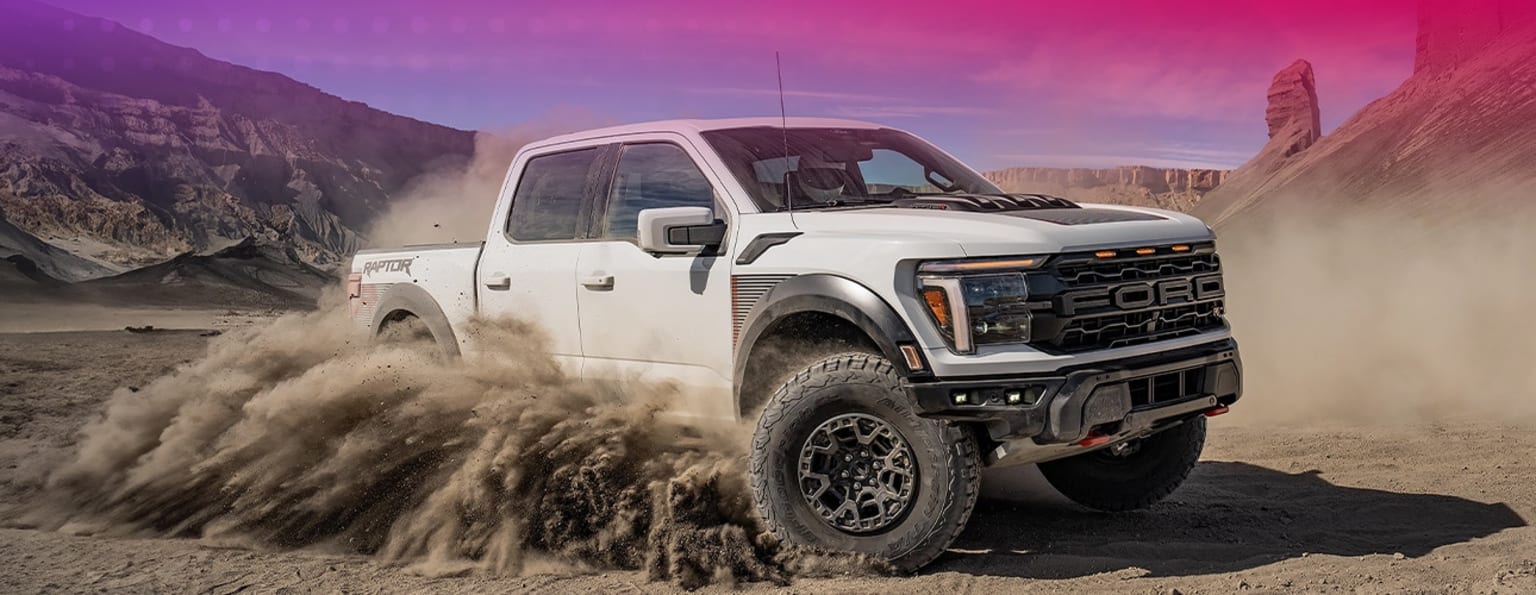A rugged, off-road pickup truck navigating rocky, mountainous terrain, kicking up dust against a vibrant, colorful sky.