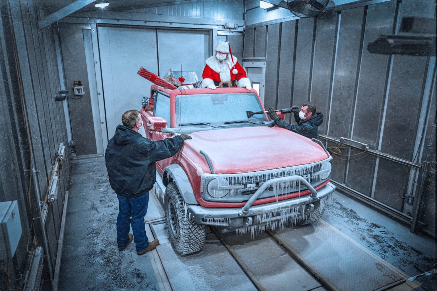 a man standing next to a red truck with a santa clause on it's hood in a garage