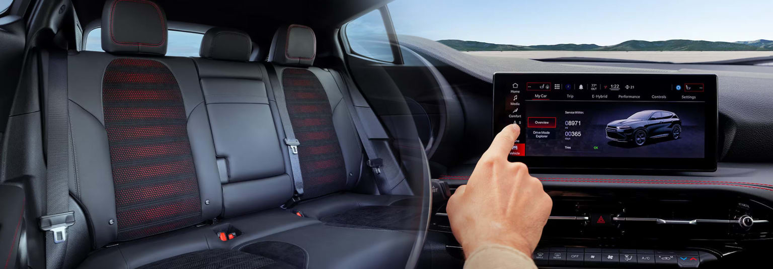 a person is driving a car with a display on the front of the car and a hand on the steering wheel