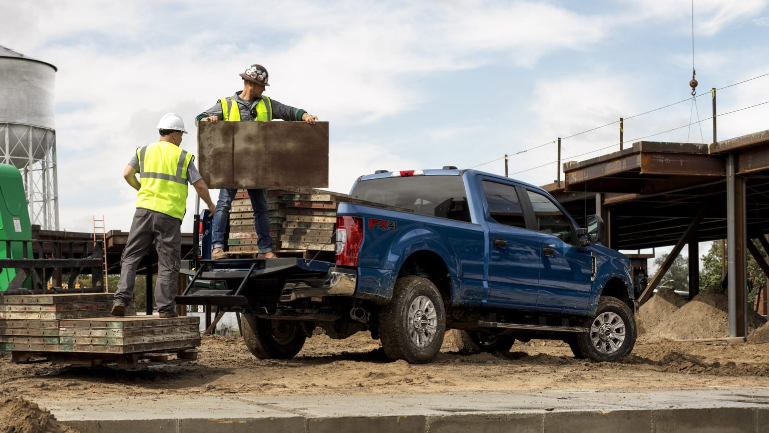 a couple of men standing on the back of a blue truck with a crate in the back of it
