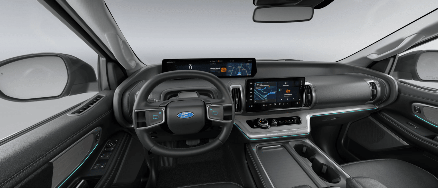 A modern car interior with a digital dashboard and steering wheel in the foreground, set against a plain, light grey background.