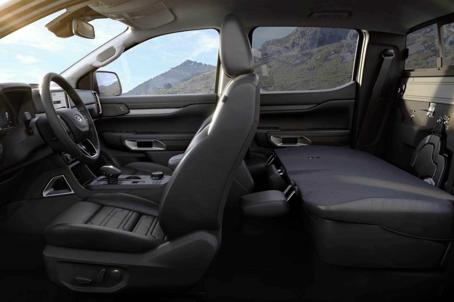 Interior of a vehicle with black leather seats and a view of mountainous terrain through the windshield and side windows.