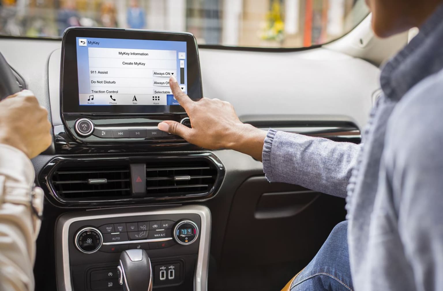 a man and a woman are sitting in a car with a tablet in the center of the car and the man is pointing at the screen