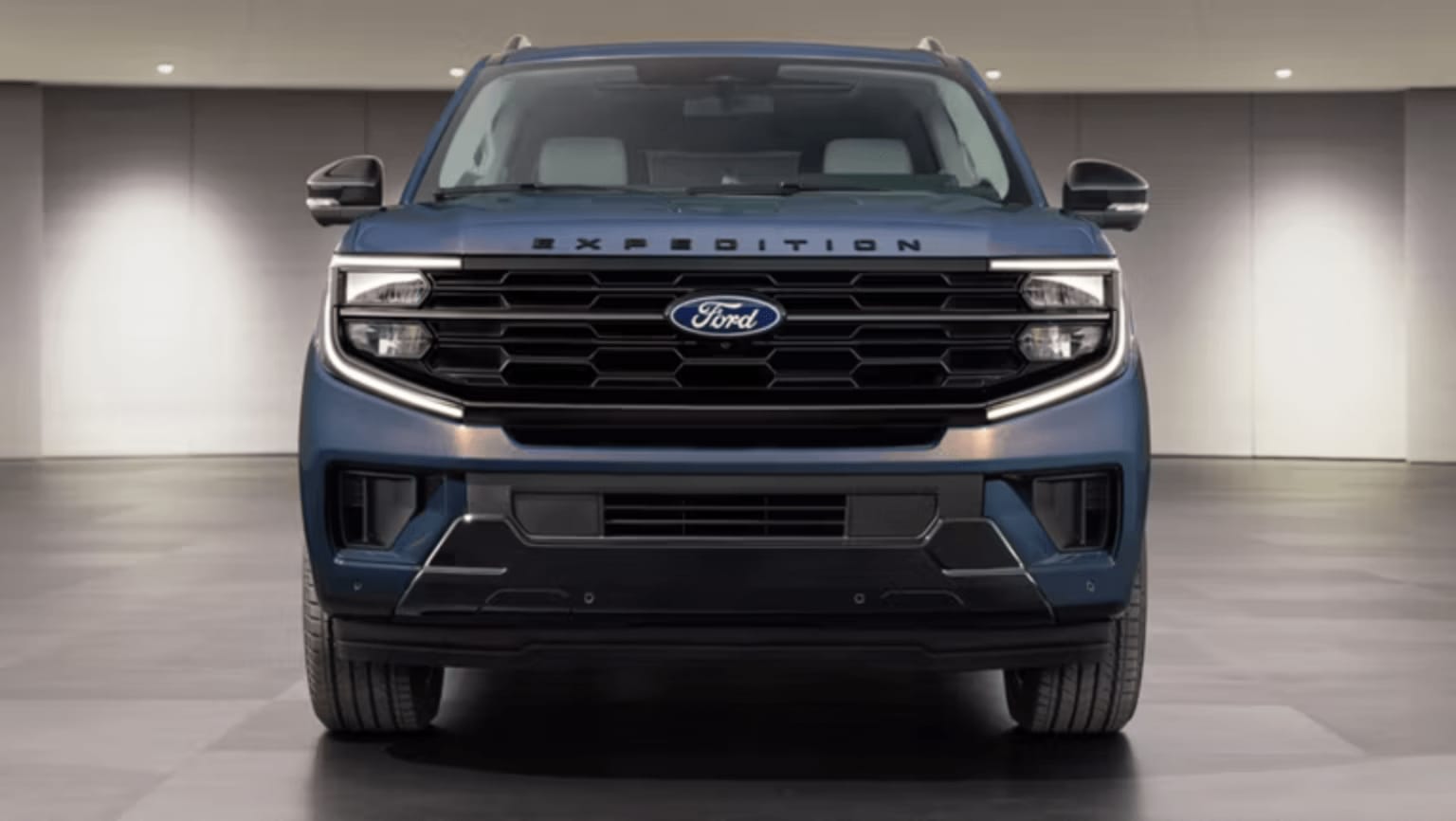 A blue SUV is front and center against a softly lit, minimalist studio background.