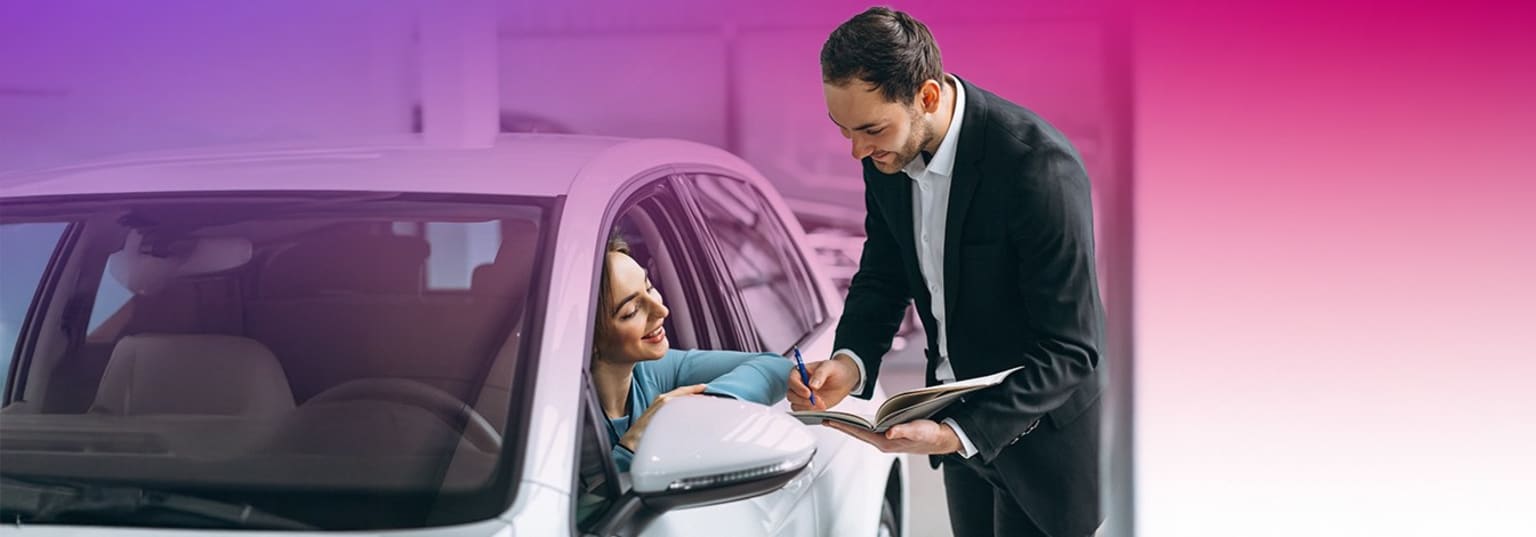 A man in a suit is leaning over a woman sitting in a car, reading a book together in a dimly lit, pink-toned environment.