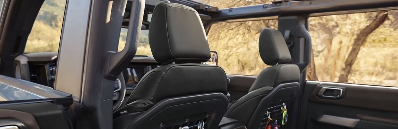 Interior of a vehicle with black leather seats and a rugged, outdoor background visible through the windows.
