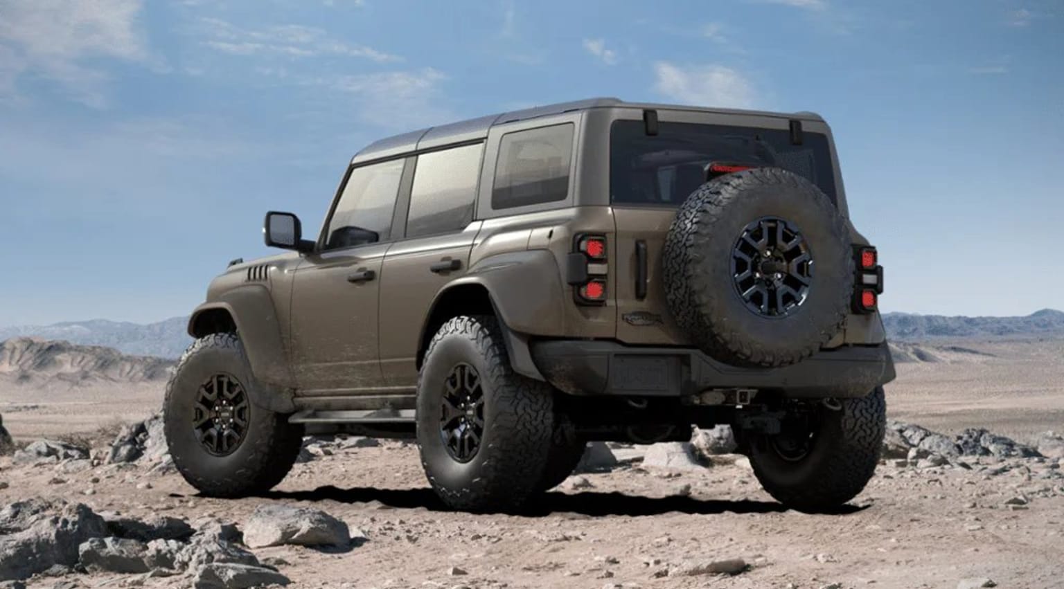 Off-road vehicle in desert landscape with large tires and sturdy frame, surrounded by rocky terrain and clear blue sky.