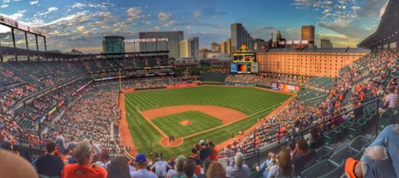 a crowd of people watching a baseball game in a stadium with a view of the city in the background