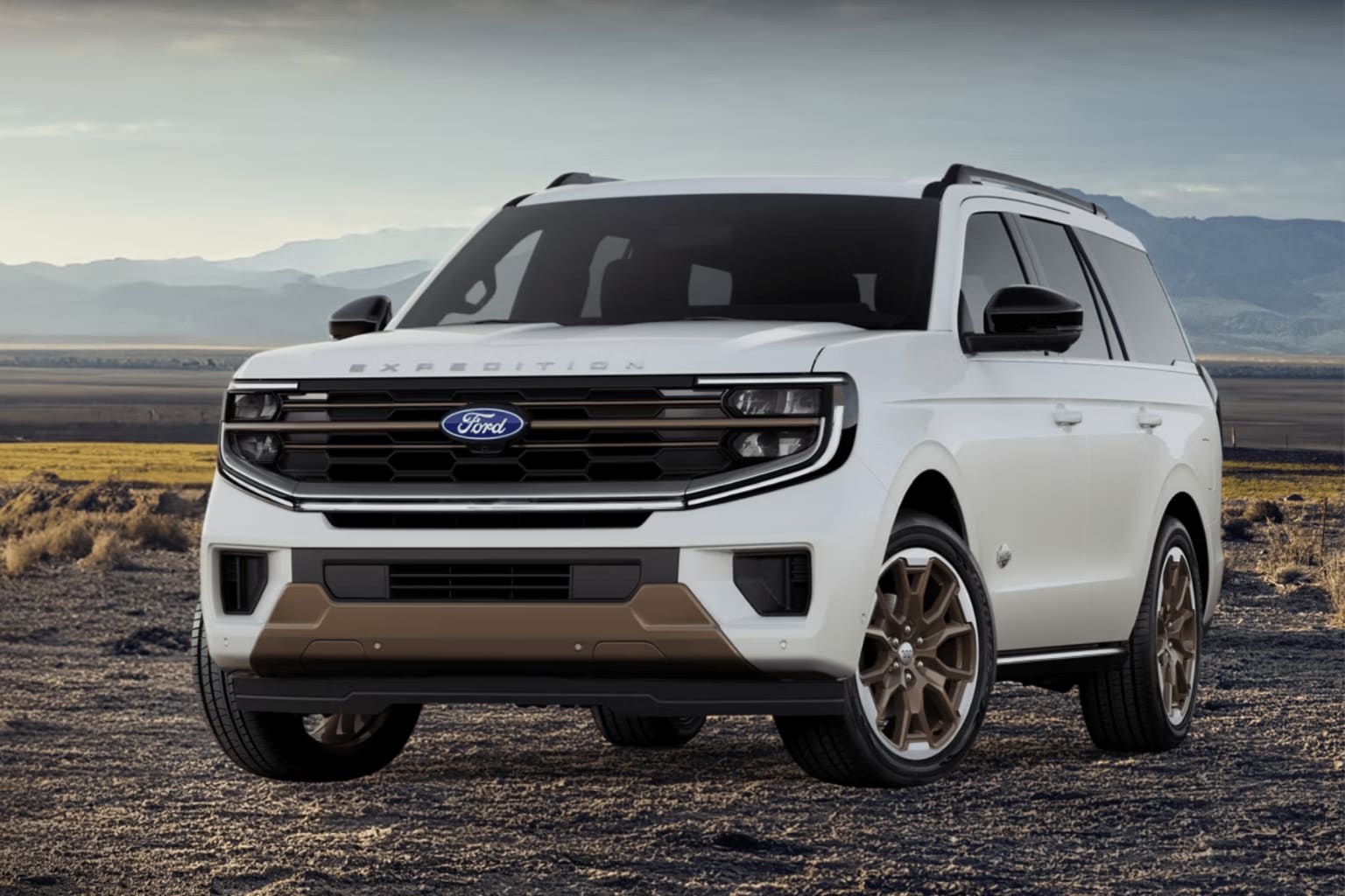 An SUV is parked on a dirt road with mountains in the background.