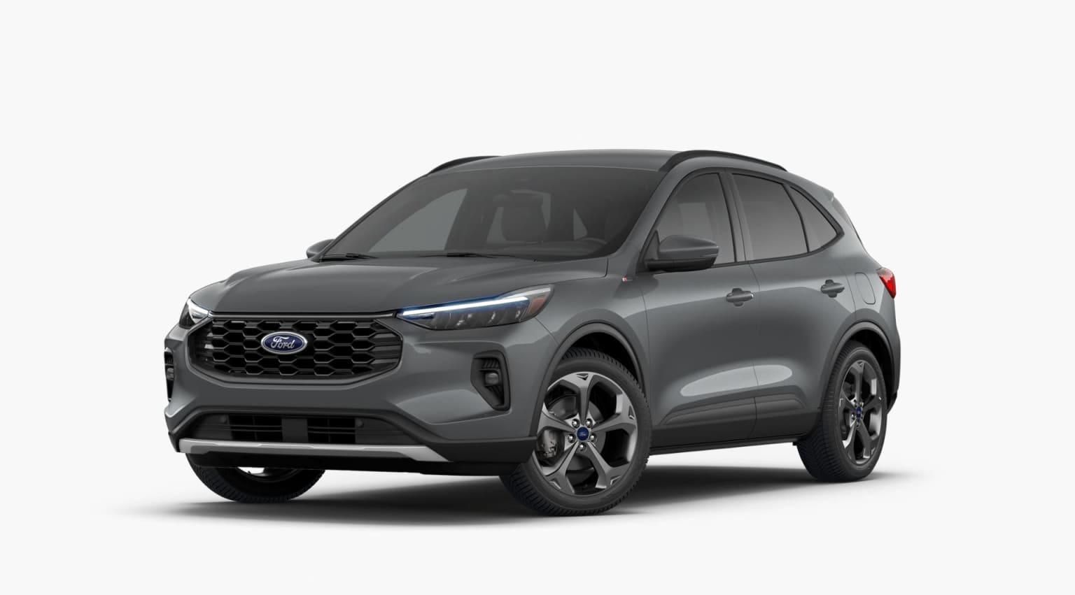 A gray SUV with a sleek, modern design stands prominently in the foreground, its bold grille and angular headlights catching the eye. The background is a plain, white setting, allowing the vehicle to be the sole focus of attention.