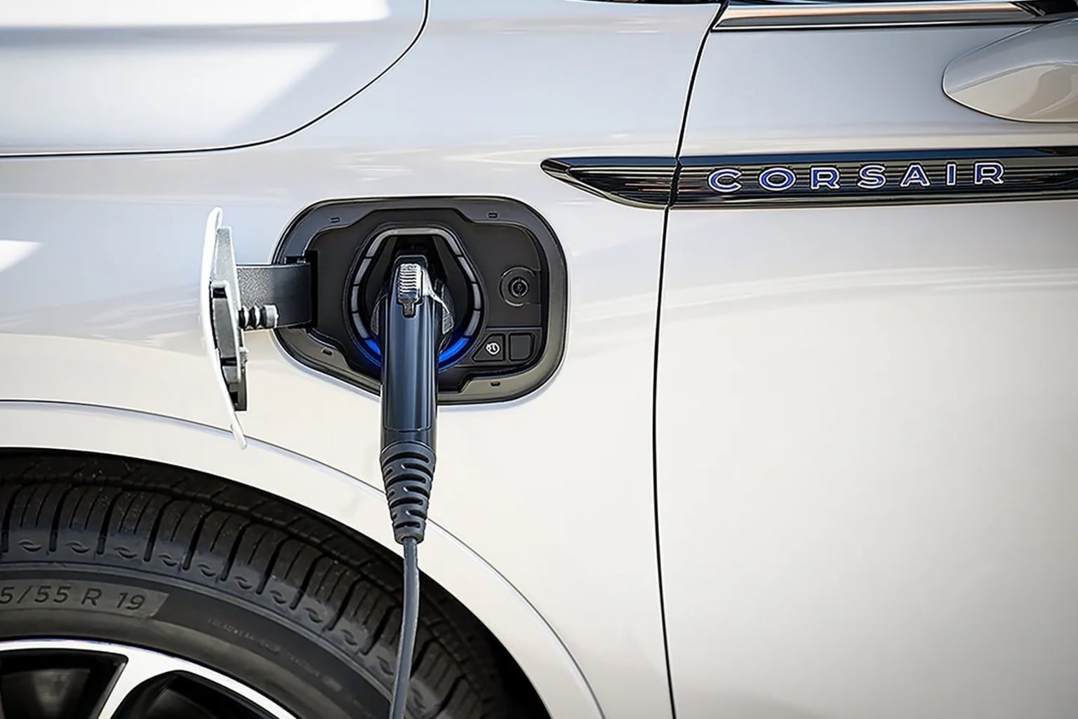 An electric vehicle is being charged, with the charging cable plugged into the vehicle's charging port.