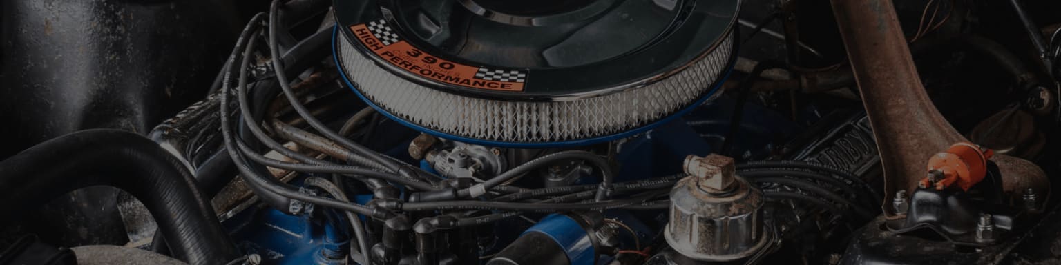 a close up of a car engine with a lot of wires and a clock on the top of it