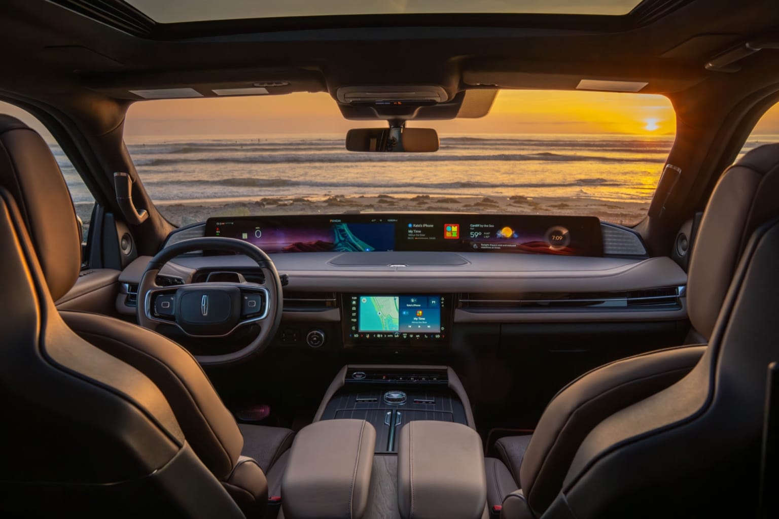 Interior of a vehicle with a dashboard and steering wheel in the foreground, showcasing a serene ocean sunset in the background.