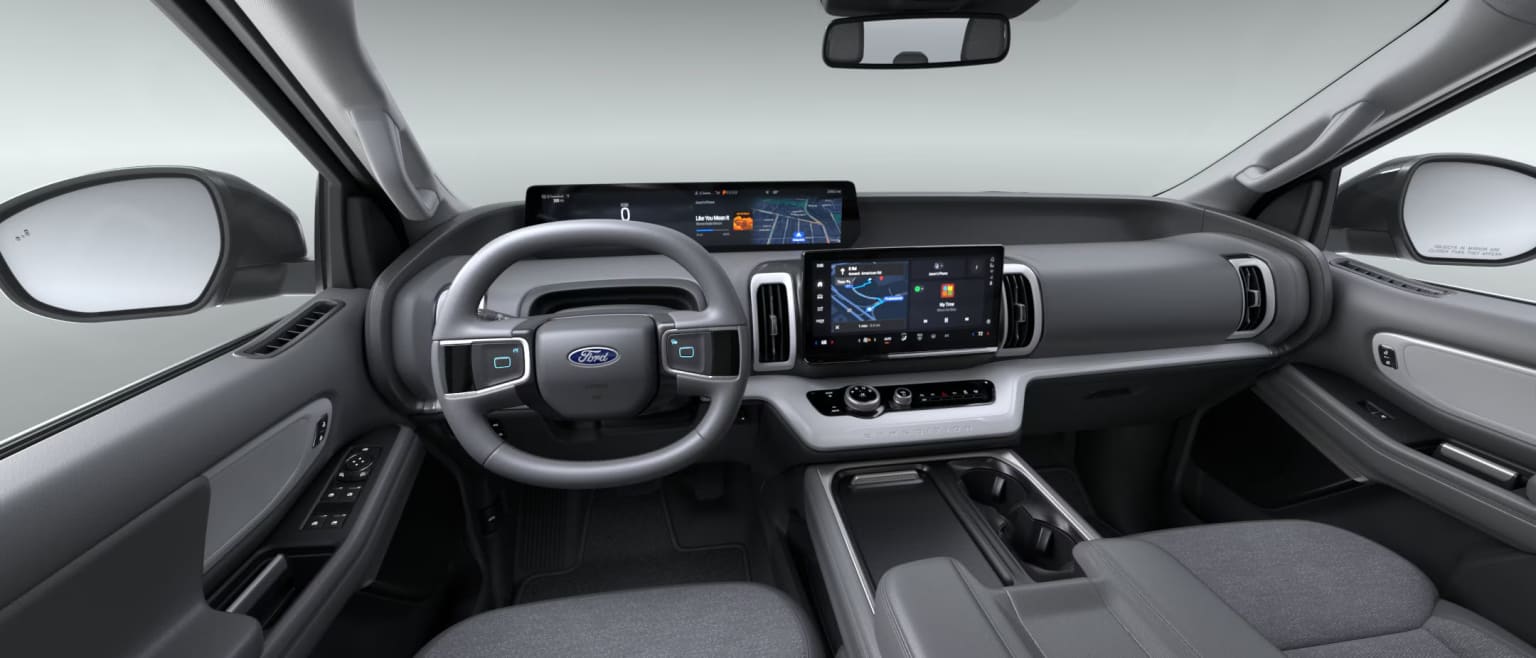 Interior of a modern vehicle with a sleek dashboard including a large touchscreen display, various controls, and a steering wheel.