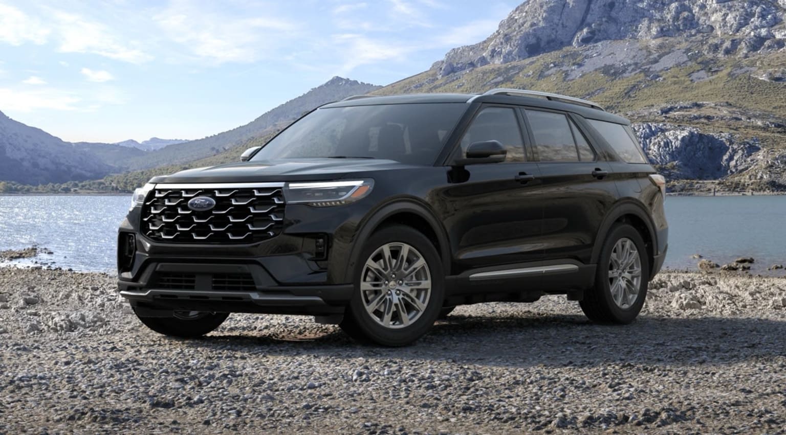 Black SUV parked on rocky shore with mountainous landscape in the background.