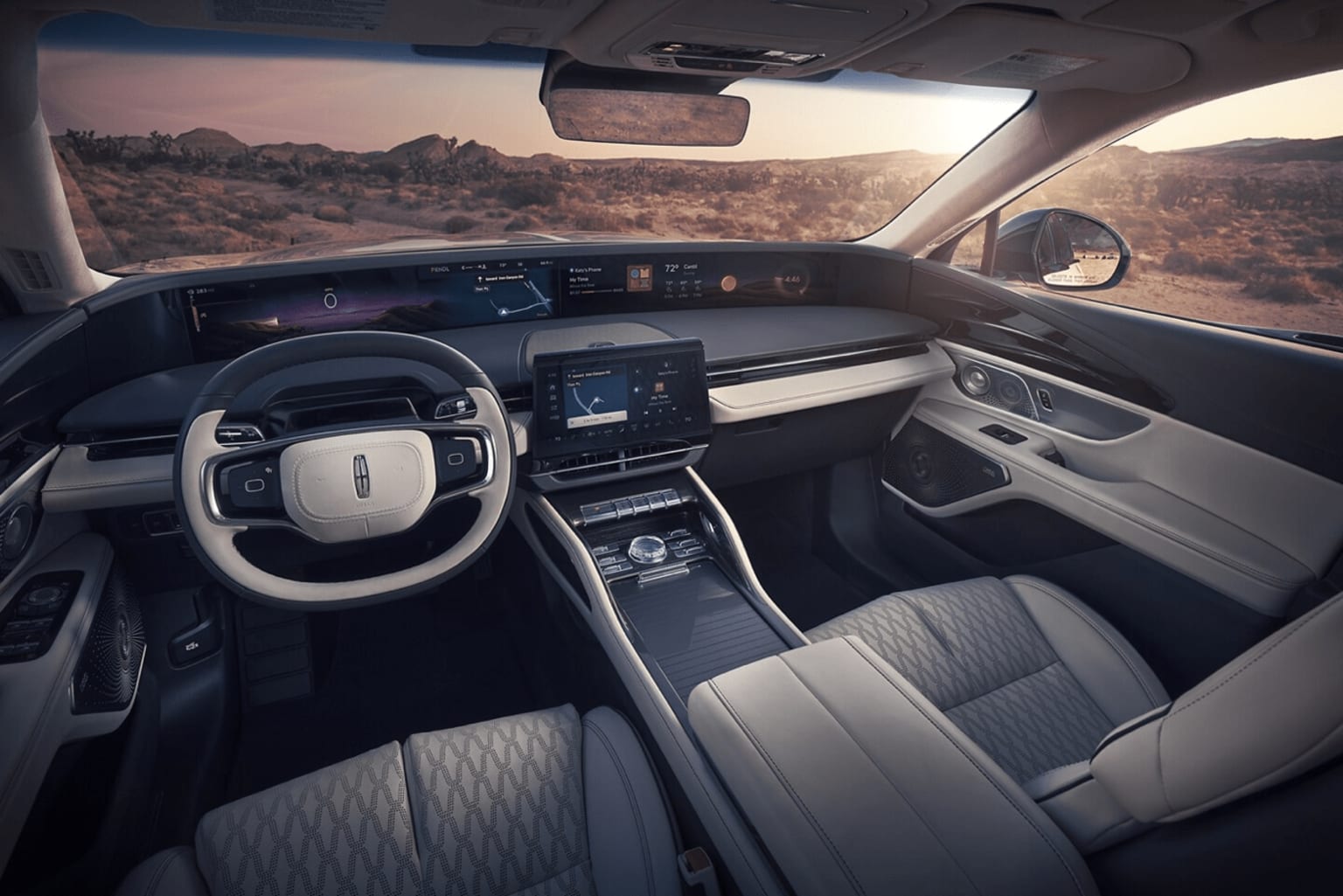Interior of a modern vehicle with a sleek dashboard and digital displays, showcasing a panoramic view of a desert landscape through the windshield.