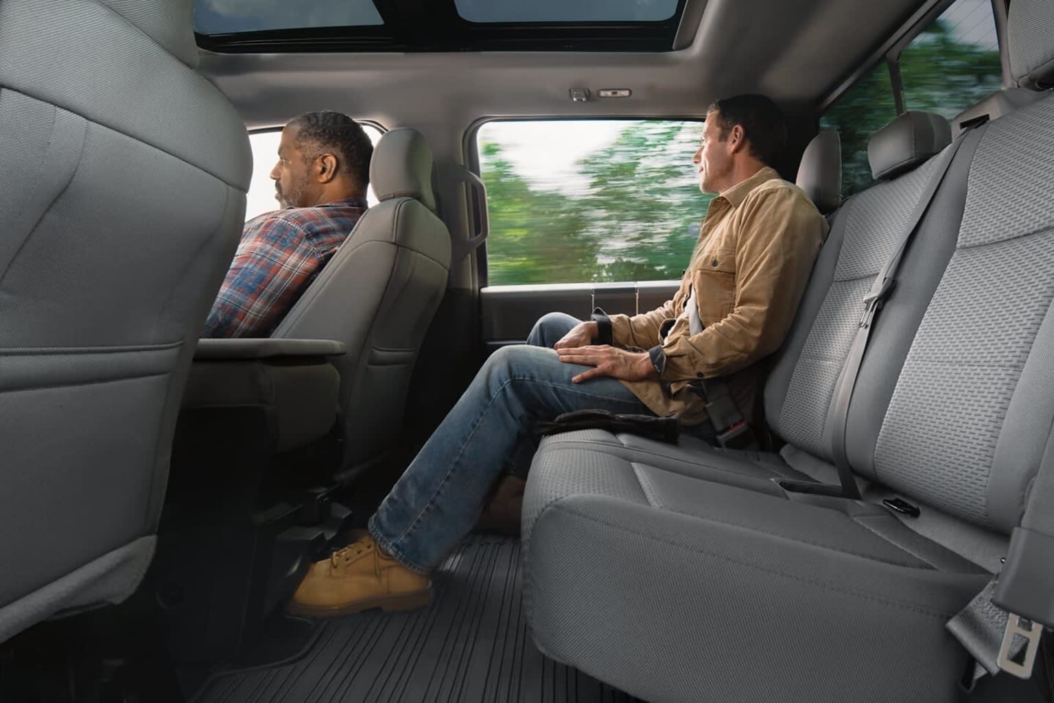 a couple of men sitting in the back of a car next to each other on a bench in front of a window