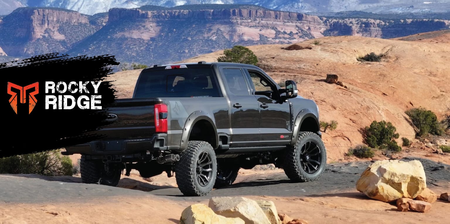 An off-road vehicle tackling a rocky terrain with cliffs in the background.