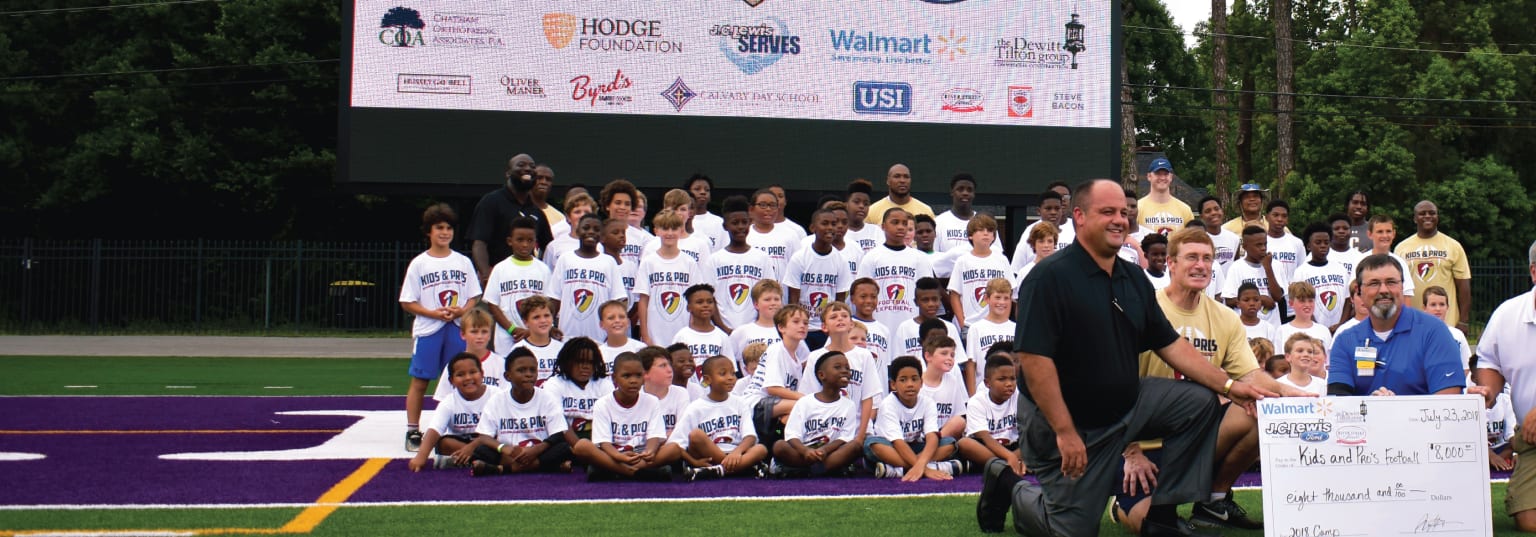 A group of young people, including a man and a woman, are posing for a picture on a soccer field.