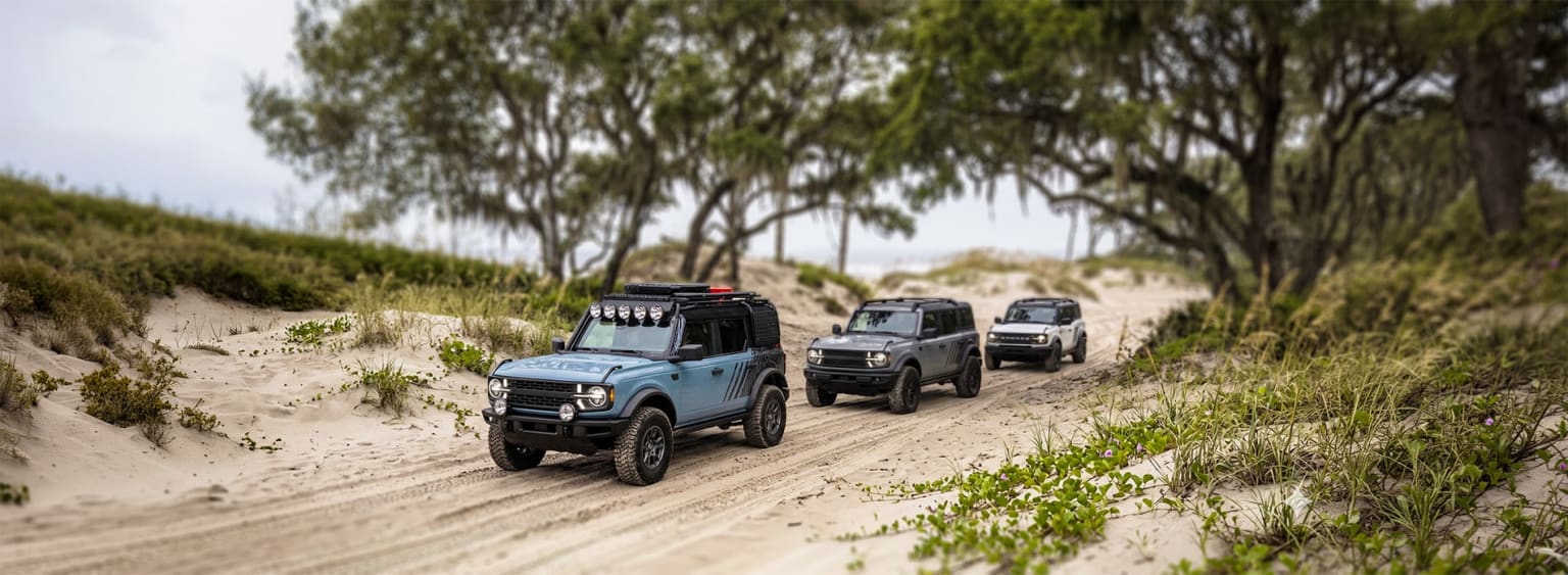 Off-road vehicles driving on dirt path in a forest.