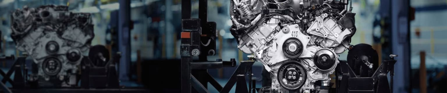 Two car engines displayed in a factory setting.