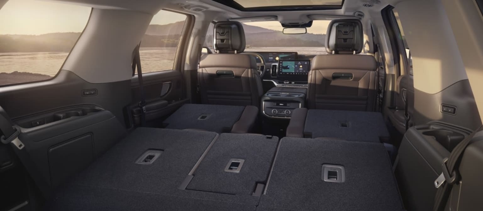 Interior of a spacious vehicle with rows of seats and ample storage space, set against a backdrop of a mountainous landscape.