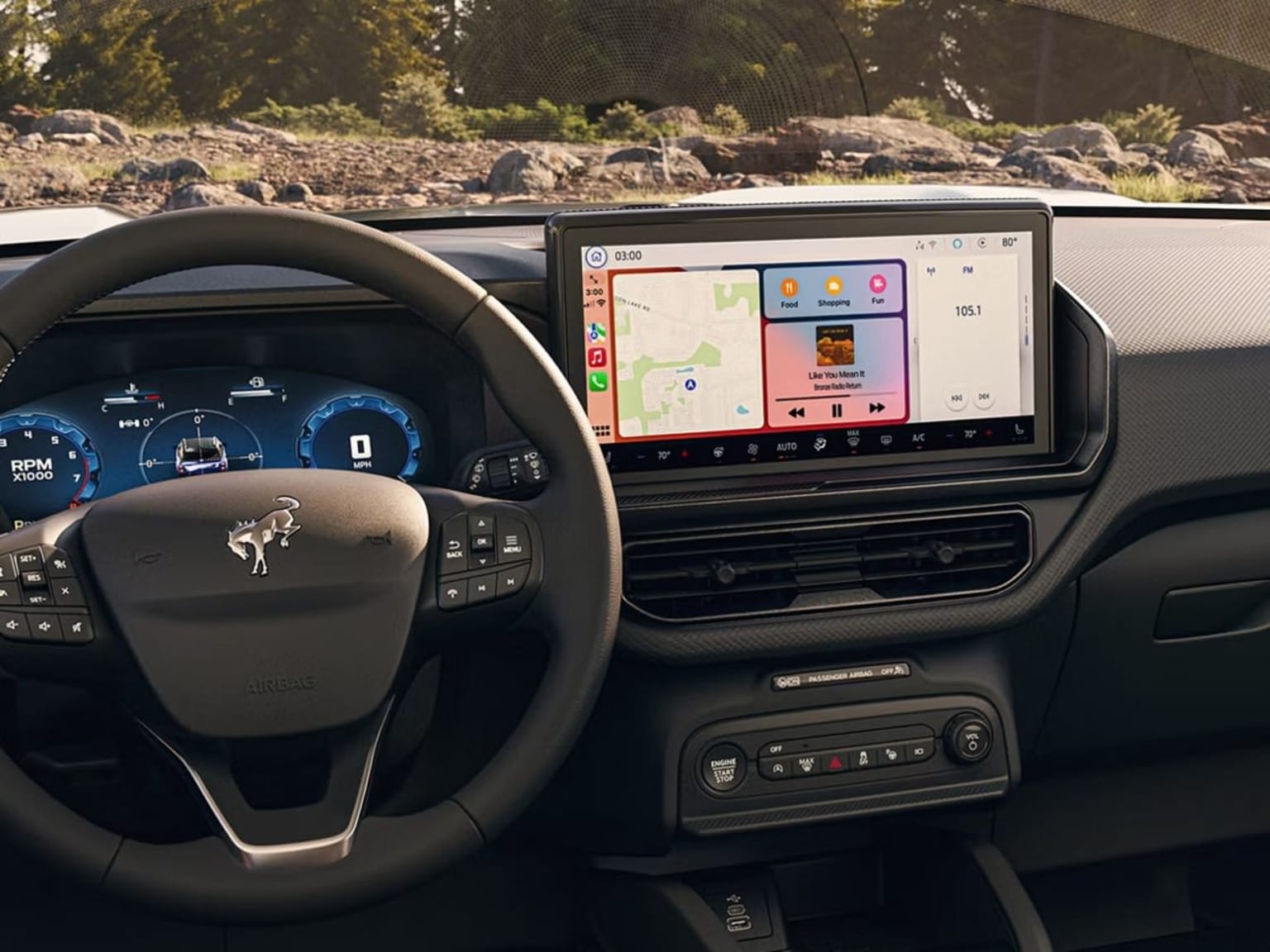 Image alt text: Modern car dashboard with large touchscreen display and digital instrument cluster, outdoor landscape in the background.
