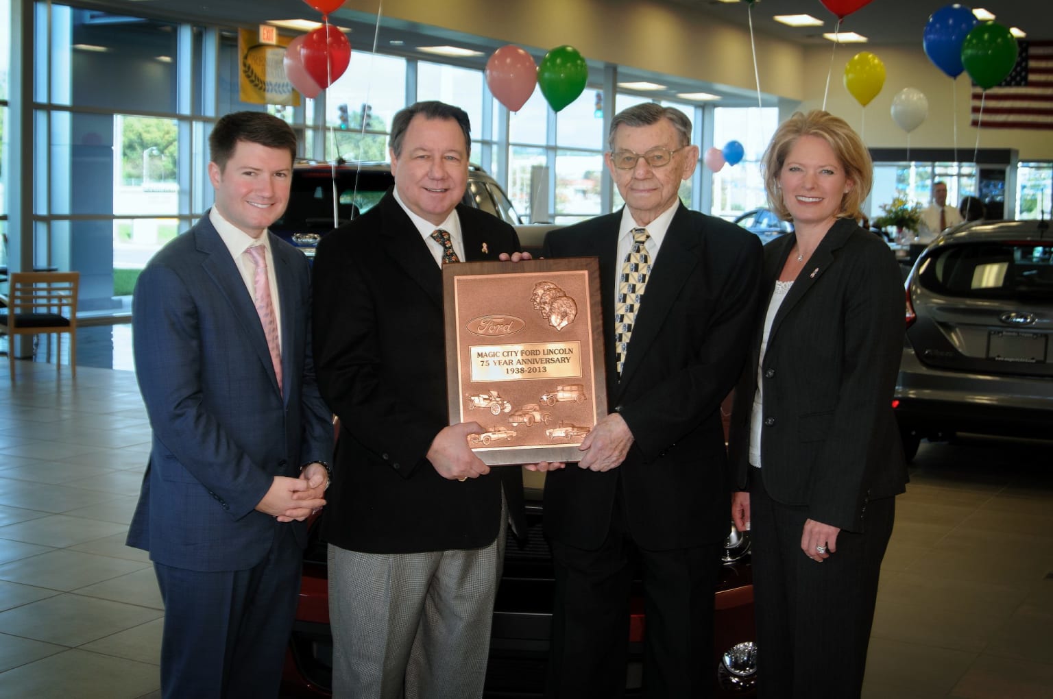 a group of people standing next to each other holding a plaque in front of a car dealers display room