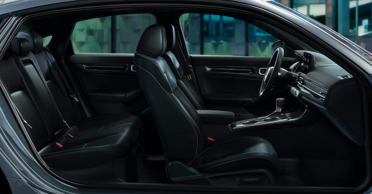 Sleek, black leather interior of a car with urban cityscape in the background.