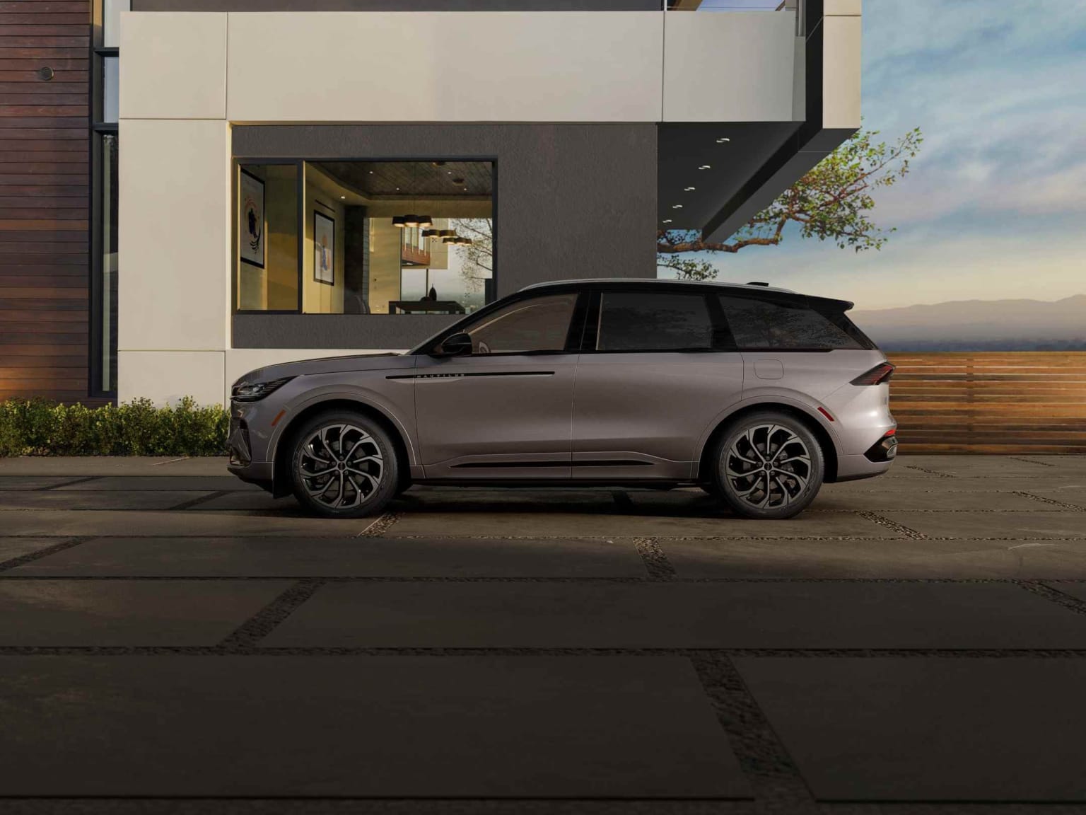 A sleek, modern SUV parked in front of a contemporary building with a cloudy sky and a few trees visible in the background.