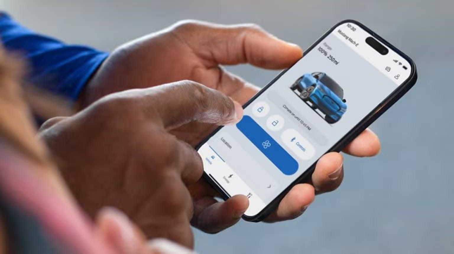 Hands holding a smartphone with an image of a blue car on the screen.