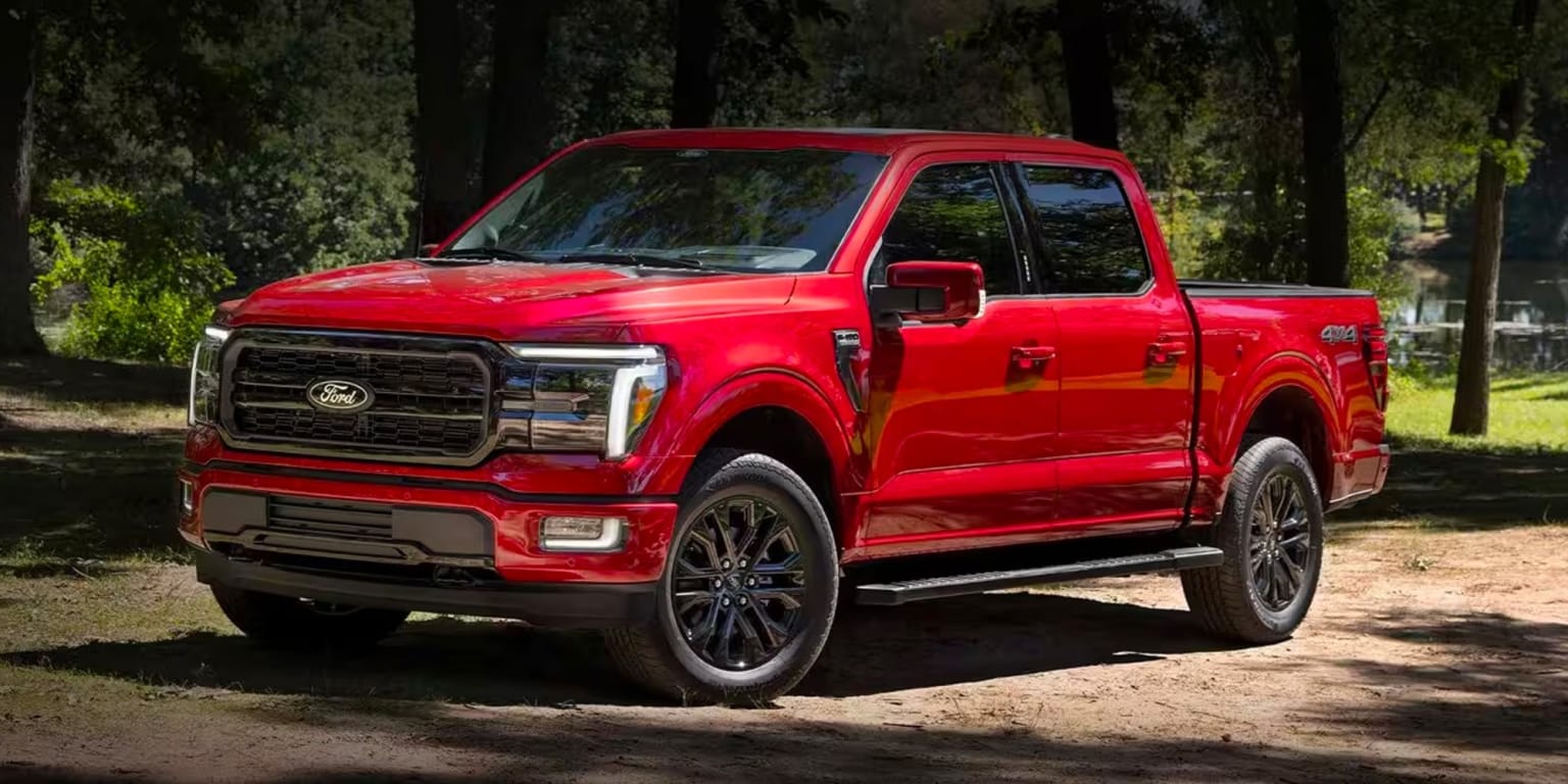 a red ford f - 150 pickup truck parked on a dirt road in a wooded area with trees in the background