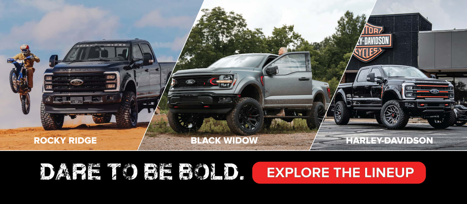 Three rugged and customized pickup trucks from a dealership are prominently featured, showcasing various unique models. The trucks are set against a backdrop of lush greenery and a clear sky, creating an outdoor, adventurous atmosphere.