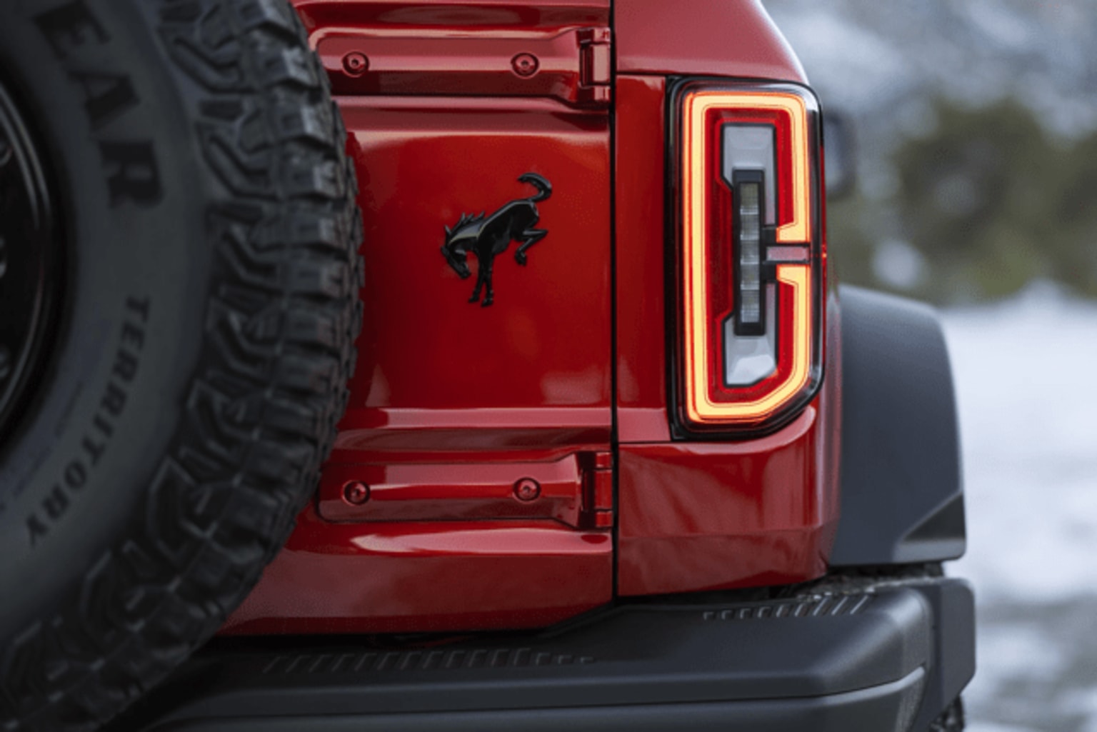 A red vehicle with a prominent logo on the rear door, set against a snowy outdoor background.