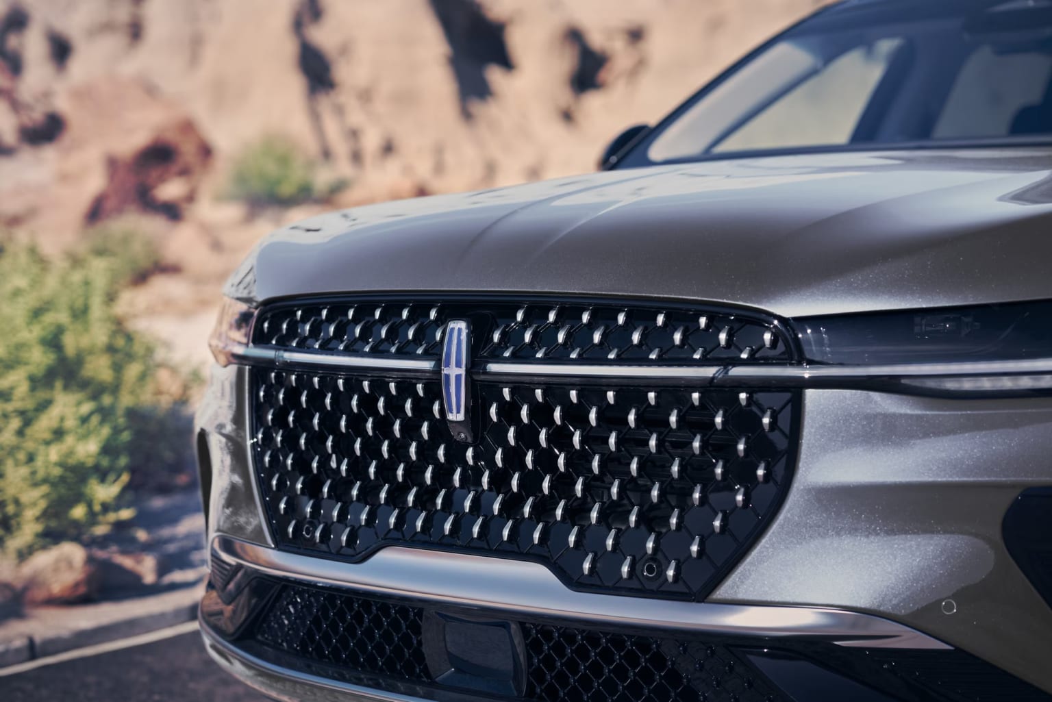 SUV parked in rugged terrain with distinctive grille design.