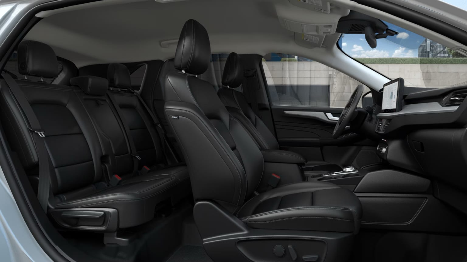 Interior of a vehicle with rows of black leather seats and a steering wheel visible in the foreground, in a garage or showroom setting.