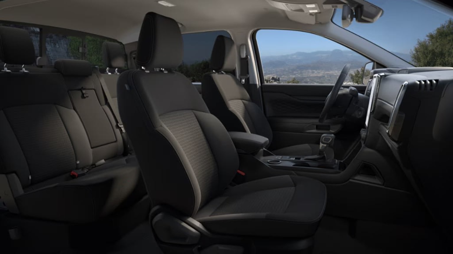The image shows the interior of a vehicle with dark leather seats and a dashboard visible in the foreground, with a mountainous landscape visible through the windshield in the background.