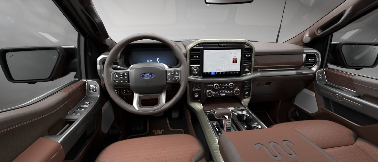 Interior of a vehicle with a steering wheel, dashboard, and various controls and displays visible, indicating a high-end or luxury design.