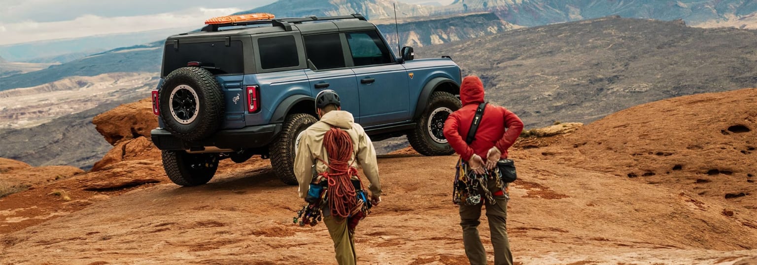 Off-road vehicle with two individuals on rocky terrain