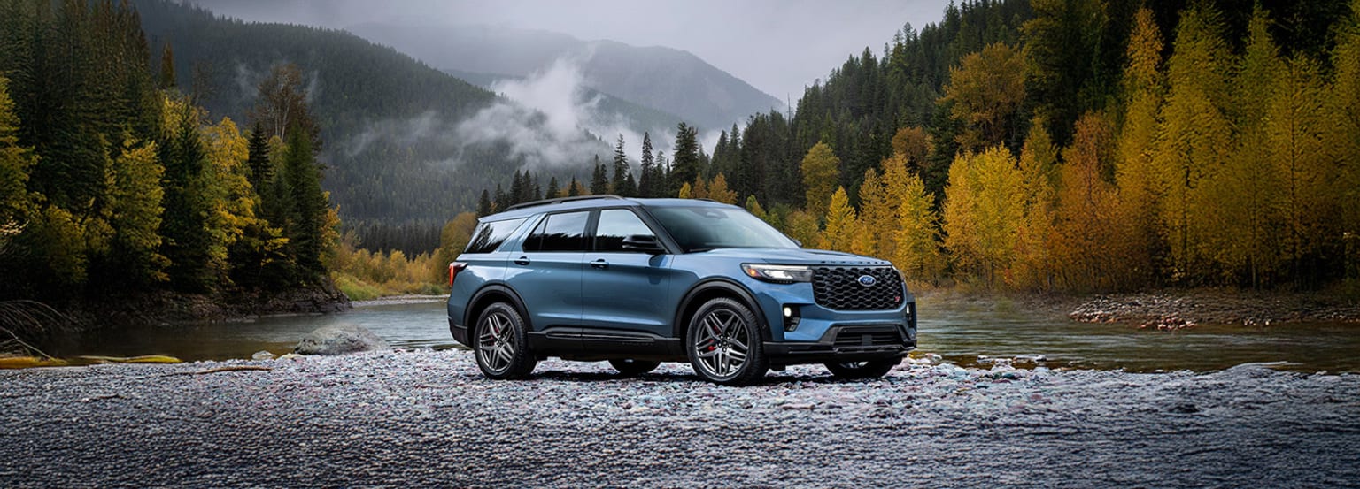 An off-road SUV in a mountain landscape with a river, autumn trees, and misty forest.
