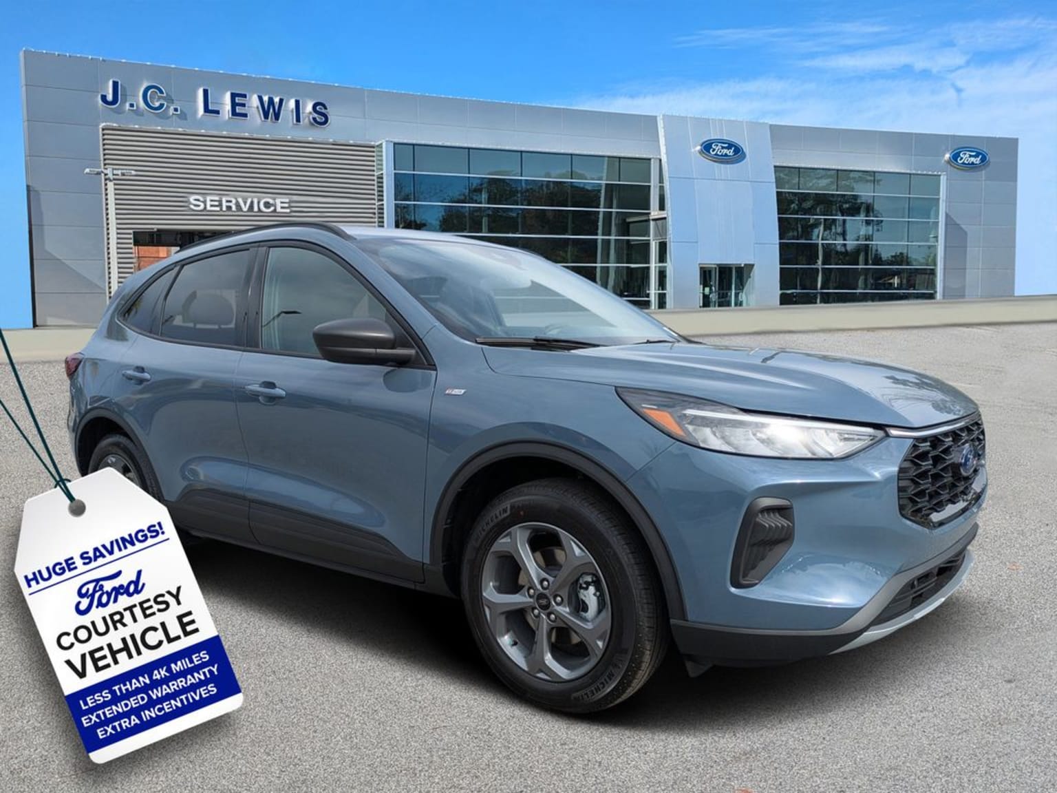 A gray SUV parked in front of a dealership, with a "Huge Savings" sign displayed on the vehicle.